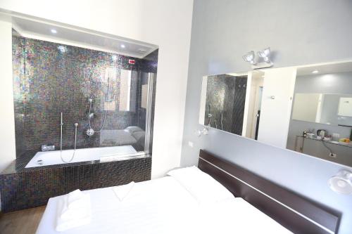 a bathroom with a tub and a bed and a mirror at KISS ME ROME Luxury Rooms in Rome