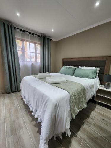 ein Schlafzimmer mit einem großen Bett mit weißer Bettwäsche und grünen Kissen in der Unterkunft Cozy and Comfort in Harrismith