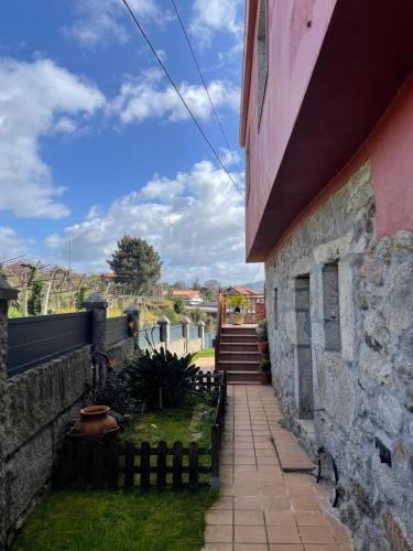 a walkway outside of a house with a stone wall at Chalet casa con piscina en ARBO Vigo in Arbo