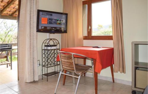 a dining room with a red table and chairs and a television at Two-Bedroom Holiday Home In Calcatoggio in Calcatoggio
