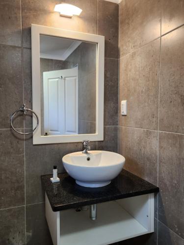 La salle de bains est pourvue d'un lavabo blanc et d'un miroir. dans l'établissement Hippo Lodge Apartments, à St Lucia
