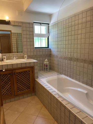 a bathroom with a tub and a sink and a mirror at Oliva House in Lagos