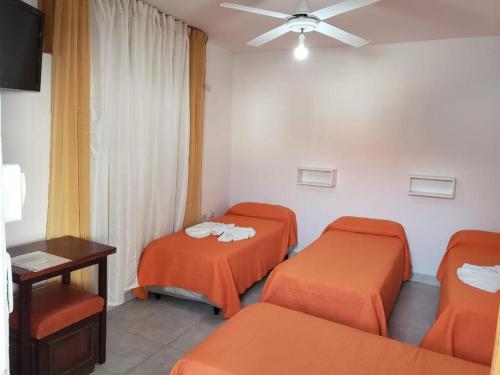 3 camas en una habitación con sábanas naranjas en Hotel Ciudad del Sol en Termas de Río Hondo