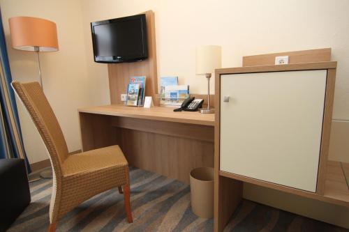 Camera con scrivania, TV e sedia. di Inselhotel Bruns a Norderney