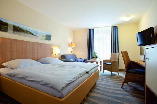 um quarto de hotel com uma cama, uma secretária e uma televisão em Inselhotel Bruns em Norderney