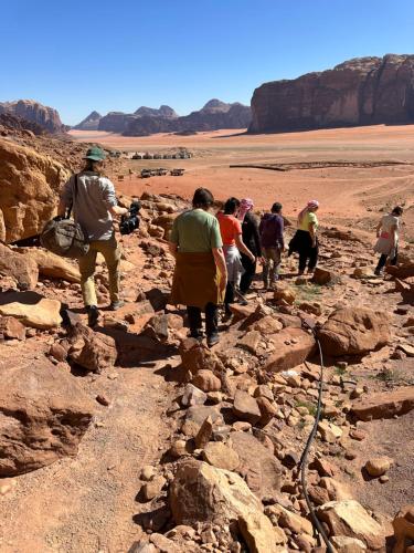 a group of people walking on a rocky path in the desert at bedouin future camp in Wadi Rum