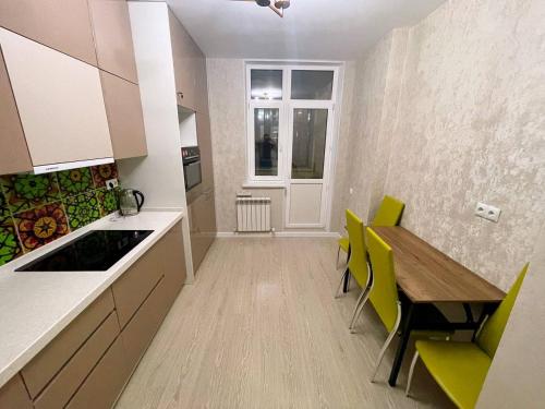 a kitchen with a wooden table and yellow chairs at Promenade Expo in Prigorodnyy