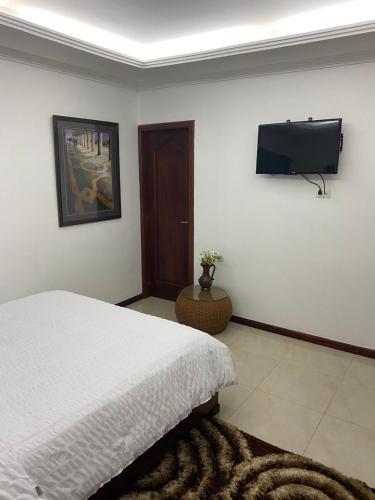 a bedroom with a bed and a flat screen tv at El Castillo de Nallig in Gualaceo