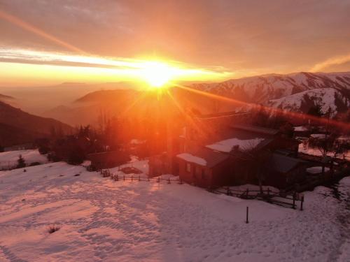 a winter sunset in the mountains with snow on the ground at Casa Farellones in Farellones