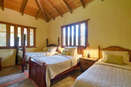 two beds in a room with windows and two bedsvisor at Fantastic Harmony Chalet in Pinar del Sol in Jarabacoa