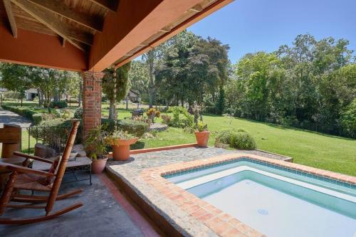 a swimming pool in a patio with a chair next to a house at Escape Chalet at Pinar del Sol in Jarabacoa in Jarabacoa