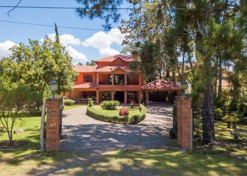 a large orange house with trees and a driveway at Escape Chalet at Pinar del Sol in Jarabacoa in Jarabacoa