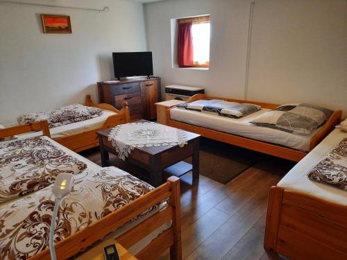a room with three beds and a television in it at Méz-Bor Szálló in Báránd