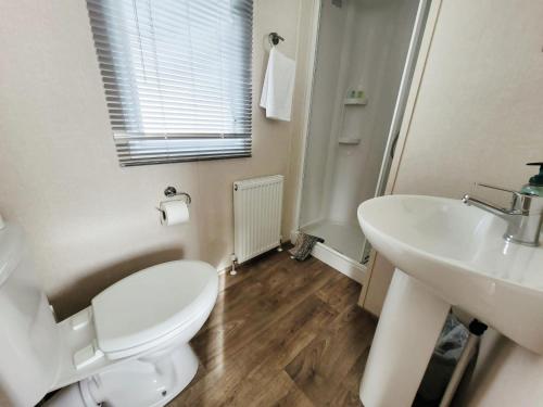 La salle de bains blanche est pourvue de toilettes et d'un lavabo. dans l'établissement Nightingale, à South Cerney