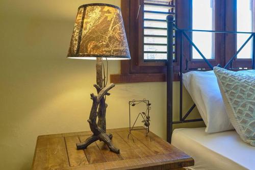 a lamp on a wooden table next to a bed at Escape Chalet at Pinar del Sol in Jarabacoa in Jarabacoa