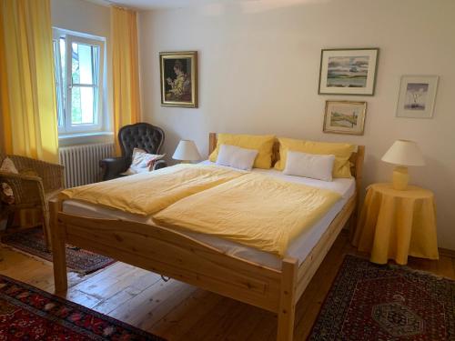 a bedroom with a large wooden bed with yellow sheets at Gästehaus Stöhr - Ihre Ferienwohnungen mit großem Garten und direktem Seezugang in Öhningen