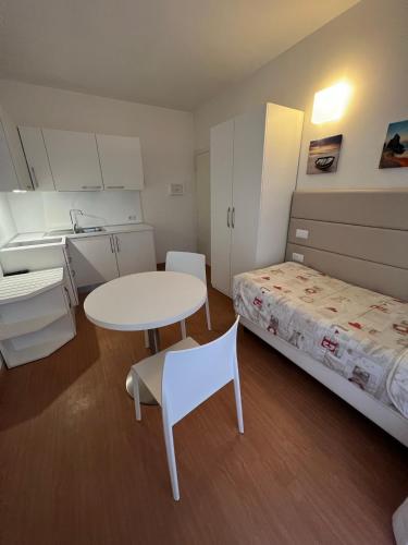 a small room with a bed and a table and a sink at Hotel Ardea in Riccione