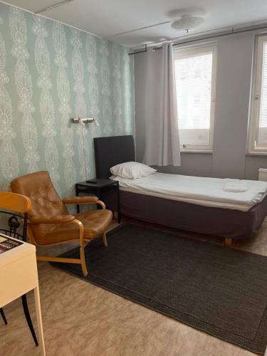 a small bedroom with a bed and a chair at Drottninggatans Vandrarhem in Karlskrona