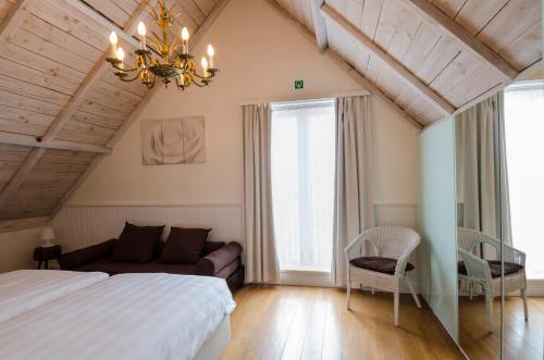 um quarto com uma cama, um sofá e um lustre em Wellnessvakantiehuis Victorello em Heuvelland
