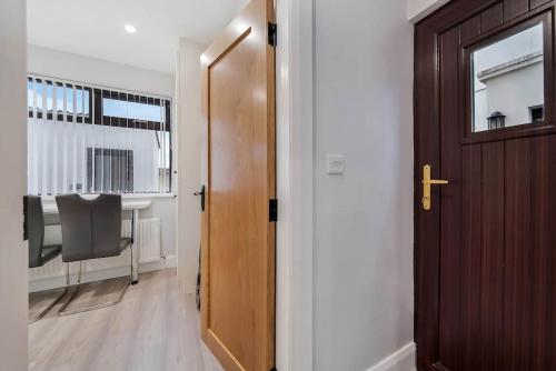 Habitación con puerta, mesa y escritorio. en Ardoyne Lodge 'Sleeping 4 Guests' en Belfast