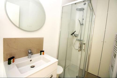 ein Bad mit einem Waschbecken und einer Dusche mit einem Spiegel in der Unterkunft Le Trident YourHostHelper in Cannes