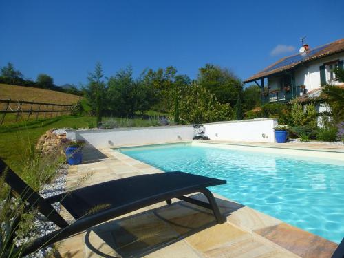 a swimming pool with a bench next to a house at Maison Aretxola in Sare