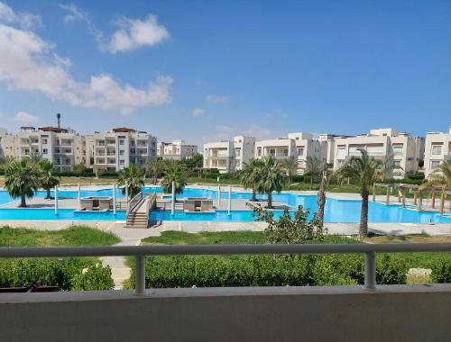 a view of a pool with palm trees and buildings at Amwaj North coast chalet in 1st floor families only in El Alamein