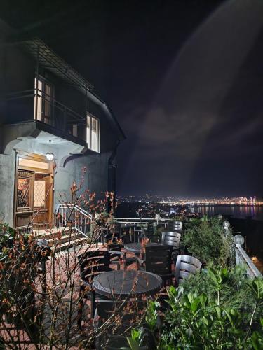 a building with tables and chairs on a balcony at night at Green Cape Tower in Batumi