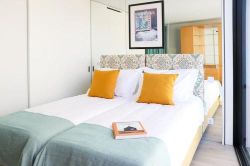 uma cama com almofadas amarelas e um livro sobre ela em T'Luz em Porto
