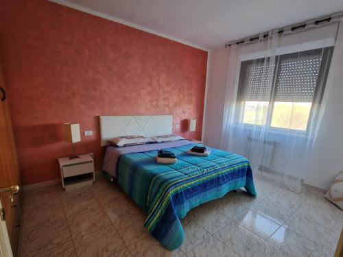 a bedroom with a bed with a blue blanket and a window at Appartamento Divino Tramonto in Altedo