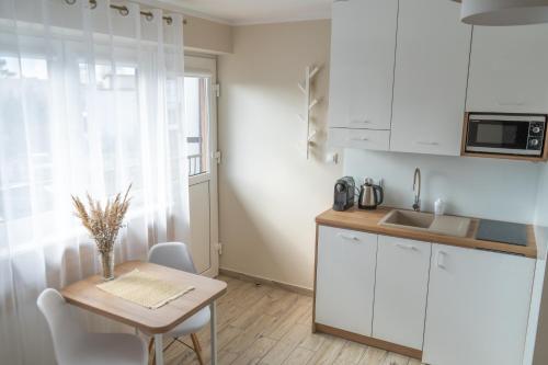 a small kitchen with white cabinets and a table and a sink at Konik Morski in Jastarnia