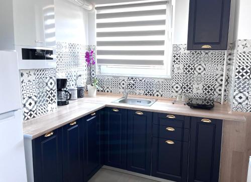 a kitchen with navy blue cabinets and a window at Mira new appartment in Otopeni near airport in Otopeni