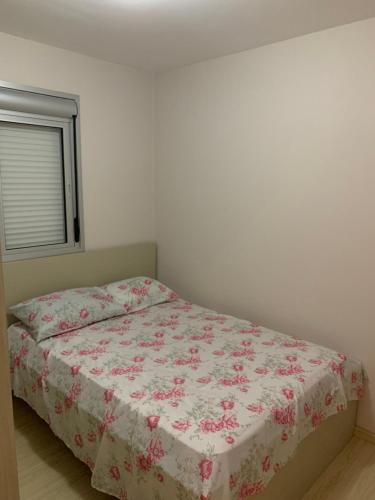 1 Schlafzimmer mit einem Bett mit Blumenbettdecke in der Unterkunft Apartamento do Aconchego in Bento Gonçalves