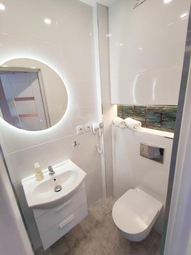 a white bathroom with a sink and a toilet at Konik Morski in Jastarnia