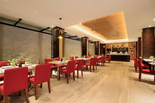 a dining room with tables and red chairs at Ohana Hotel Kuta in Kuta