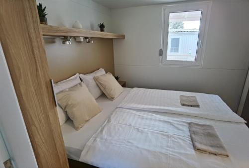 a bedroom with a bed with white sheets and a window at Adria summer home in Biograd na Moru