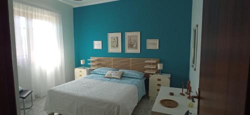 a bedroom with blue walls and a bed and a window at Holiday Home Tropicana in Mascali