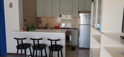 a kitchen with three bar stools and a white refrigerator at Home Tropicana in Mascali