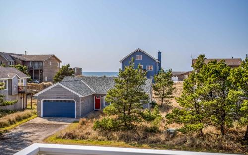 a house with a blue garage in a residential neighborhood at Pelicans Watch - Meredith Lodging in Pacific City