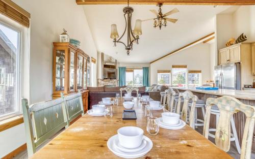 a dining room with a table with white dishes on it at Pelicans Watch - Meredith Lodging in Pacific City