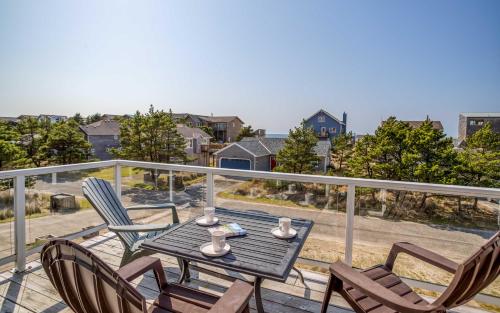 a patio with a table and chairs on a balcony at Pelicans Watch - Meredith Lodging in Pacific City