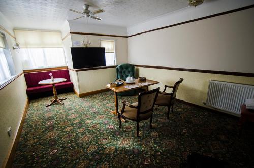 エルギンにあるElgin City Centre Torr House hotelのテーブルと椅子とテレビのある部屋