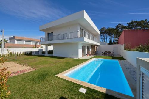 a villa with a swimming pool in front of a house at Aroeira Villa w/ Pool near Beach, By TimeCooler in Aroeira