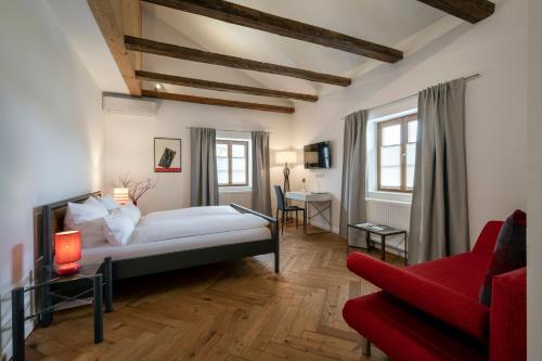 1 dormitorio con 1 cama y 1 sofá rojo en Gasthaus Unterwirt en Fridolfing