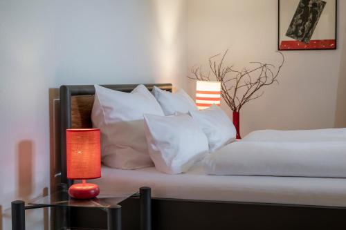 a bed with white pillows and a table with a lamp at Gasthaus Unterwirt in Fridolfing
