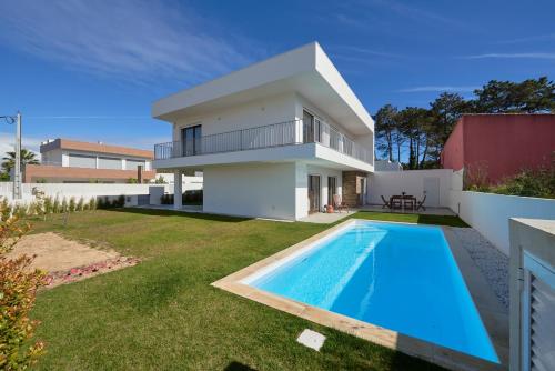a villa with a swimming pool in front of a house at Aroeira Villa w/ Pool near Beach, By TimeCooler in Aroeira