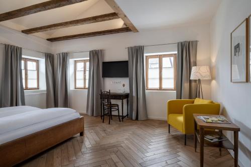 a hotel room with a bed and a yellow chair at Gasthaus Unterwirt in Fridolfing