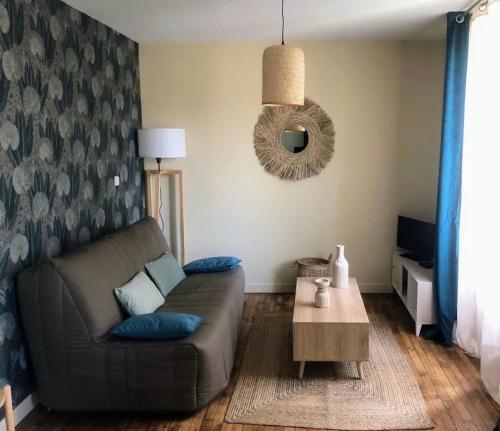 un soggiorno con un divano e un tavolo di Logement à Brive avec terrasse et climatisation - près de la gare et du centre-ville - Wifi et Stationnement gratuit a Brive-la-Gaillarde