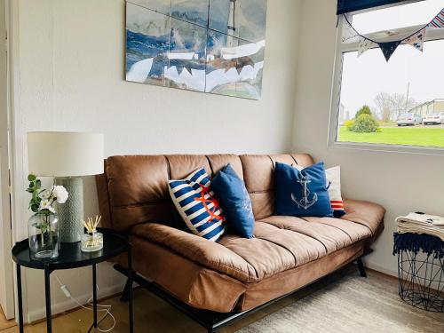 um sofá castanho com almofadas azuis numa sala de estar em “SEA HEAVEN “ chalet in Sandown Bay Holiday Park em Brading