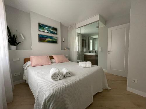 Burgos Señorial by Exclusive Burgos Apartments في برغش: غرفة نوم بسرير ابيض عليها مناشف